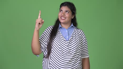 Young-overweight-beautiful-Indian-businesswoman-against-green-background