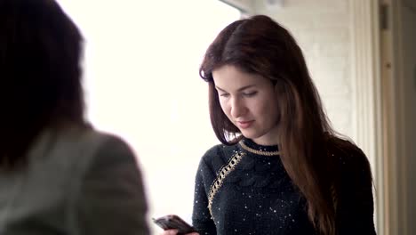 Woman-using-mobile-phone-at-table-during-meeting-with-friend-in-cafe