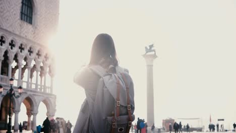 Happy-female-tourist-taking-smartphone-photos-of-amazing-San-Marco-square-in-Venice-Italy-with-sunlight-lens-flare.