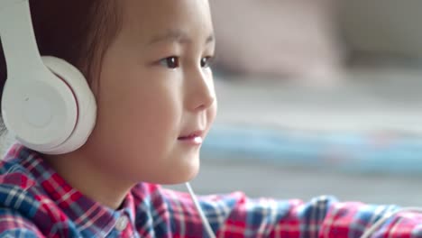 Little-Asian-Girl-in-Headphones-Moving-to-Music-on-Smartphone