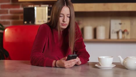 Mujer-joven-navegando-por-internet,-revisar-novedades-en-redes-sociales-durante-el-uso-de-smartphone-en-la-cocina.