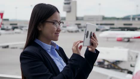 Mujer-bonita-joven-navegando-por-internet-con-tableta-digital-en-edificio-público