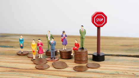 Miniature-people-standing-on-piles-of-coins