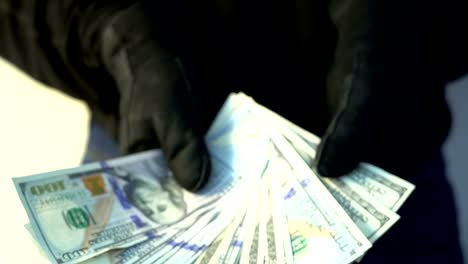 crime-concept-man-in-black-leather-gloves-holding-pile-of-money