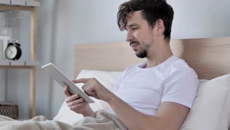 Junge-Mann-mittels-Tablet-beim-liegen-im-Bett