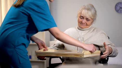 Nurse-bringing-medications-to-old-woman,-caring-about-patient-in-hospital