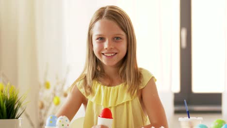 happy-girl-showing-colored-easter-egg-at-home