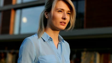 Close-up-portrait-of-a-beautiful-business-woman-holding-and-using-tablet-outside.-Modern-architecture-building-background