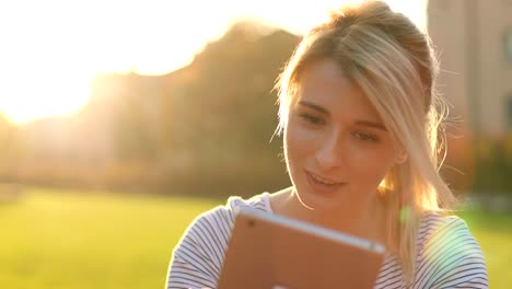 Portrait-of-young-female-student-using-tablet-computer-in-the-park.-Girl-doing-online-shopping-on-tablet-pc