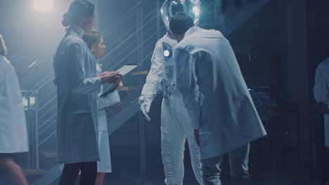 Diverse-Team-of-Aerospace-Scientists-and-Engineers-Wearing-White-Coats-have-Discussion,-Use-Computers,-Design-New-Space-Suit-Adapted-for-Galaxy-Exploration-and-Travel.-Constructing-Astronaut-Suit