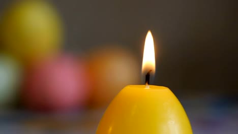 Candles-made-in-shape-of-easter-egg.-Burning-candles.-Green,-orange,-yellow.-Sliding,-close-up.