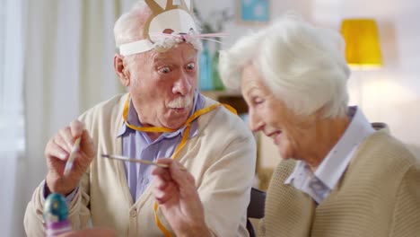 Elderly-Couple-Painting-Eggs-and-Laughing