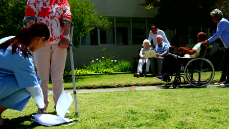 Seitenansicht-von-Hausärztin,-die-im-Garten-des-Pflegeheims-4k-eine-Oberpatientin-untersucht