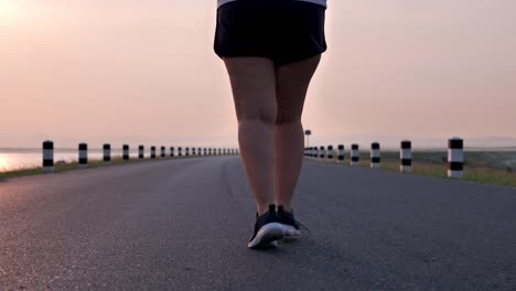 Overweight-Asian-women-jogging-in-the-street-in-the-early-morning-sunlight.-concept-of-losing-weight-with-exercise-for-health.-Slow-motion,-Bottom-view