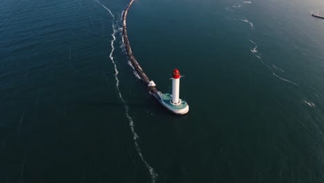 Aerial-shot-of-white-lighthouse-near-sea-port,-360-view