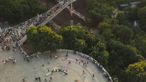 Eine-Menschenmenge-auf-einer-Fußgängerbrücke-ist-am-Frühlingsabend-zu-sehen.-Luftaufnahme.-Eine-neue-Fahrrad-Fußgängerbrücke-im-Zentrum-der-Hauptstadt-der-Ukraine,-der-Stadt-Kiew.-Ausflüge-und-Spaziergänge-für-Touristen