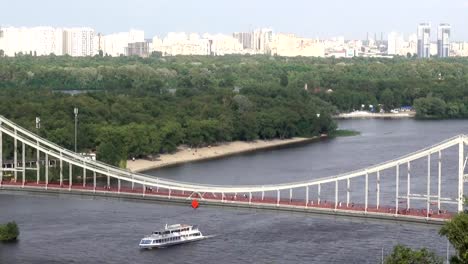 Fußgängerbrücke-über-den-Dnjepr-und-vorbei-fahrendes-Boot.