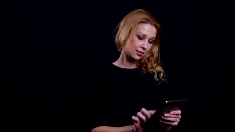 Closeup-portrait-of-adult-attractive-redhead-female-using-the-tablet-with-background-isolated-on-black