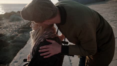 Man-is-stroking-head-of-his-beloved-woman-in-wheelchair-on-sea-coast