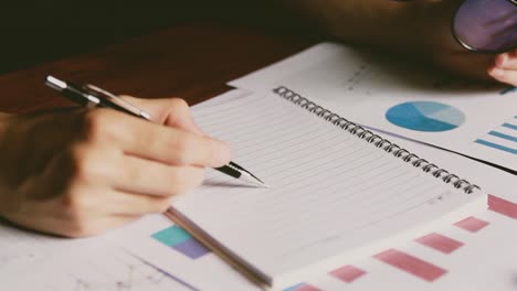 businessman-Writing-paper-and-using-calculator-Calculating-bonus(Or-other-compensation)-to-employees-to-increase-productivity.-on-desk.Selective-Focus