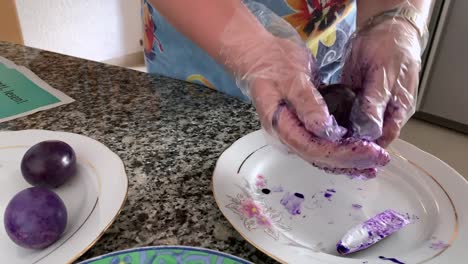 A-woman-in-gloves-paints-eggs