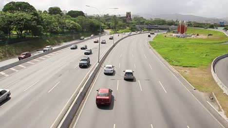 Many-cars-and-trucks-driving-on-road-in-a-large-modern-urban-city-area