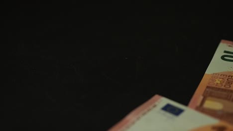 Banknotes-10-euro-slowly-falling-on-the-black-table.-Closeup.-Slow-motion