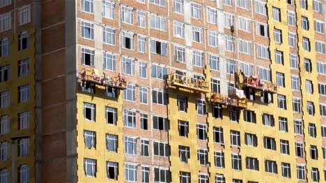 Construction-hoists-with-workers-on-the-facade-of-the-house.