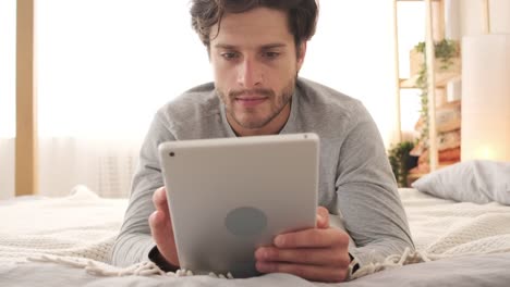 Man-using-digital-tablet-in-bed