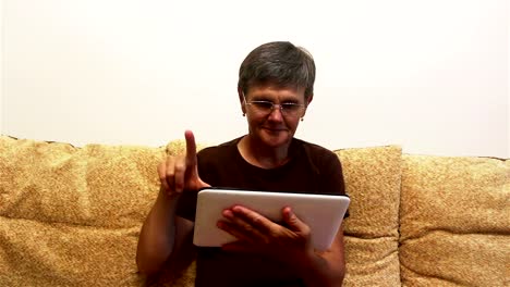 Attraktive-erwachsene-Frau-arbeiten-auf-ihrem-Tablet,-während-auf-einem-Sofa-zu-Hause-sitzen.