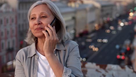 Mujer-envejecida-hablando-en-el-teléfono-celular-en-el-techo