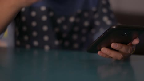 Woman-using-smart-phone-on-the-desk-and-drinking-a-cup-of-coffee-at-home.