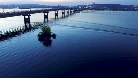 Boats-sail-under-the-bridge-at-dusk