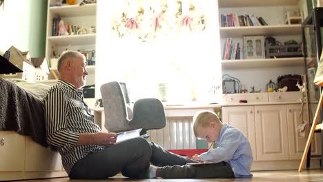 Opa-sieht-Fotoalbum-mit-seiner-Hochzeit,-kleiner-Junge-mit-elektronischen-Tablet