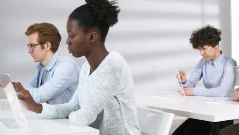 Gruppe-von-College-Studenten-mit-transparenten-futuristischen-Tablets-in-der-Klasse