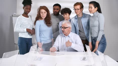 Profesor-Senior-Demostrando-a-los-estudiantes-nuevo-material-en-la-pantalla-interactiva-de-REALIDAD-Aumentada