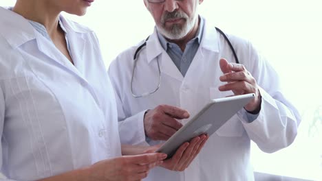 Medical-team-two-doctors-using-tablet,-shake-hands,-closeup