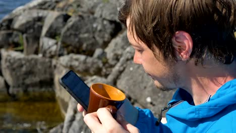 Kerl-trinkt-Kaffee-aus-Tasse-Surfen-Internet-mit-Telefon