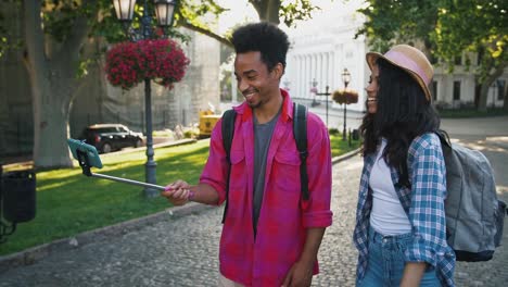 Afro-american-man-and-woman-recording-video-for-subscribers-on-mobile-phone-while-walking-along-city-street