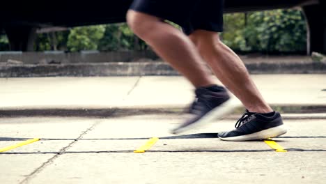 Close-up-legs-sportsman-training-with-agility-ladder-equipment.