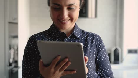 Indian-woman-working-on-tablet-electronic-device-standing-indoor