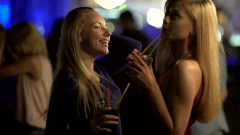 Seductive-hot-ladies-drinking-cocktails,-moving-sexy-bodies-to-music-at-disco