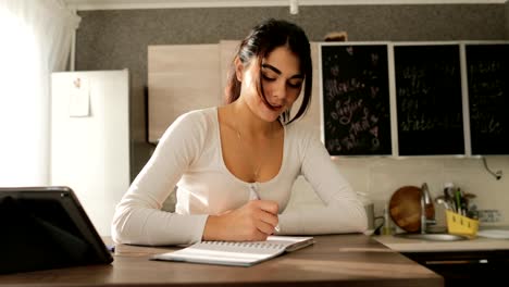 Joven-estudio-en-la-escritura-de-la-cocina-de-Tablet-computadora-hermosa-chica-estudiante-trabajo-en-la-mañana-en-el-interior