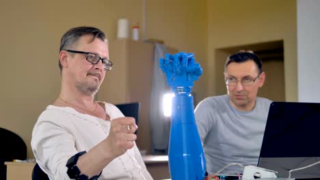 Mid-shot-of-the-two-men-testing-bionic-robotic-hand.