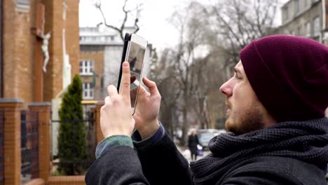 Un-joven-toma-una-fotografía-de-la-iglesia-con-una-tableta