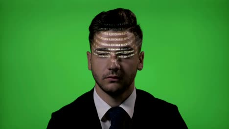 Atractivo-macho-hacker-vestida-como-un-hombre-de-negocios-cuyo-código-blockchain-refleja-en-su-rostro-sobre-un-fondo-de-pantalla-verde