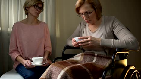 Wheelchair-mother-and-daughter-sitting-together-in-nursing-home,-support-visit