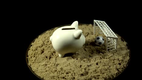 A-white-piggy-bank-stands-on-a-sandy-beach-and-spins-on-a-black-background.