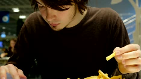 Handsome-man-eating-fast-food-and-uses-tablet-close-up