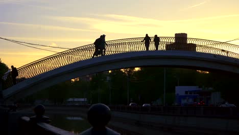 siluetas-de-personas-que-cruzan-el-canal-en-un-puente-jorobado